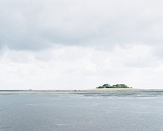 Insel Hallig von weit entfernt bei blau-grauem Wetter