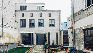 Atelierhaus mit Anbau und schwarzen Fenstern mit Blick in denGarten