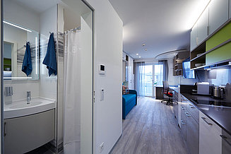 Blickwinkel in ein Apartment des Gebäude-Komplex Brucklyn, wobei Einblick ins Bad und Wohnzimmer gestattet wird
