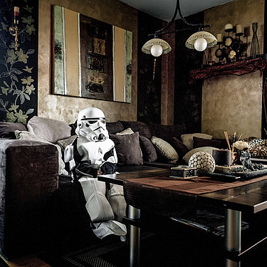 Als Star Wars Figur verkleidete Person sitzt auf einer Couch in einem Wohnzimmer.